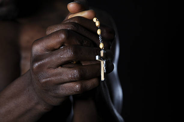 Male hands holding rosary and crucifix. Low key lighting Male hands holding rosary and crucifix. Low key lighting